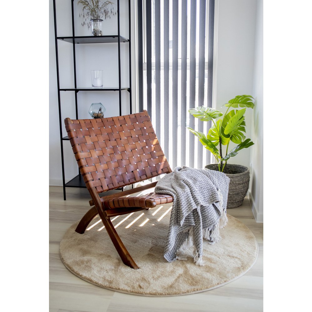 Fauteuil Perugia en teck et cuir tressé dans un salon contemporain avec plante et plaid – ambiance