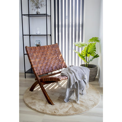 Fauteuil Perugia en teck et cuir tressé dans un salon contemporain avec plante et plaid – ambiance