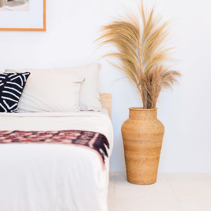 Vase KIDUNG fermé avec couvercle posé à côté d'un lit en bois naturel