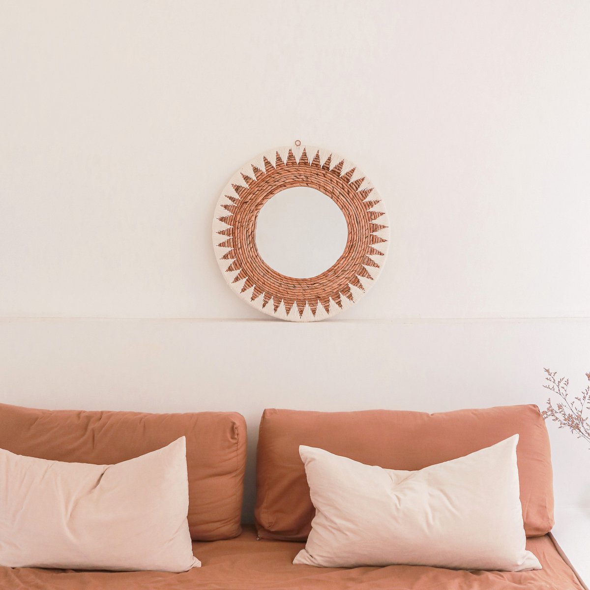 Miroir AWAN posé contre un mur blanc au-dessus d'un canapé terracotta